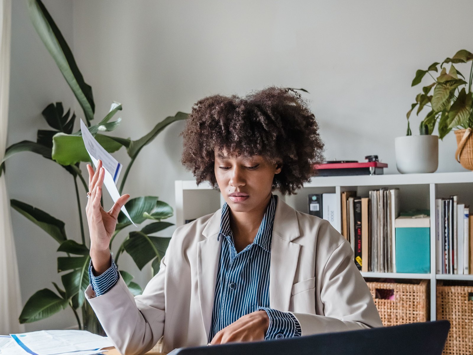 Woman reviewing documents beside a laptop as part of a human fact-checking process.