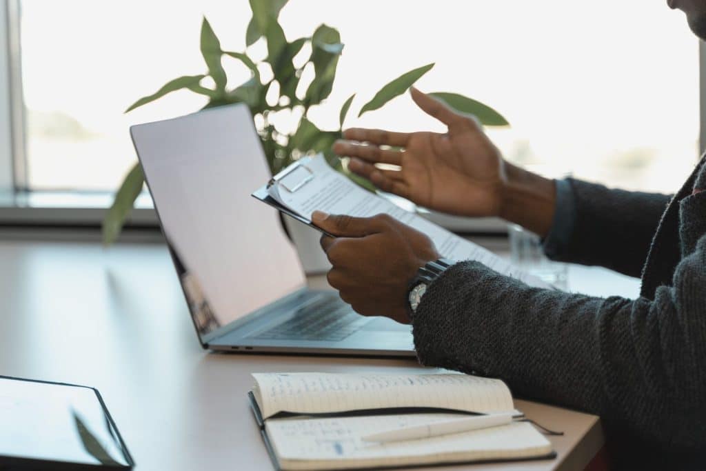 Professional reviewing a document beside a laptop, representing source-grounded AI answers