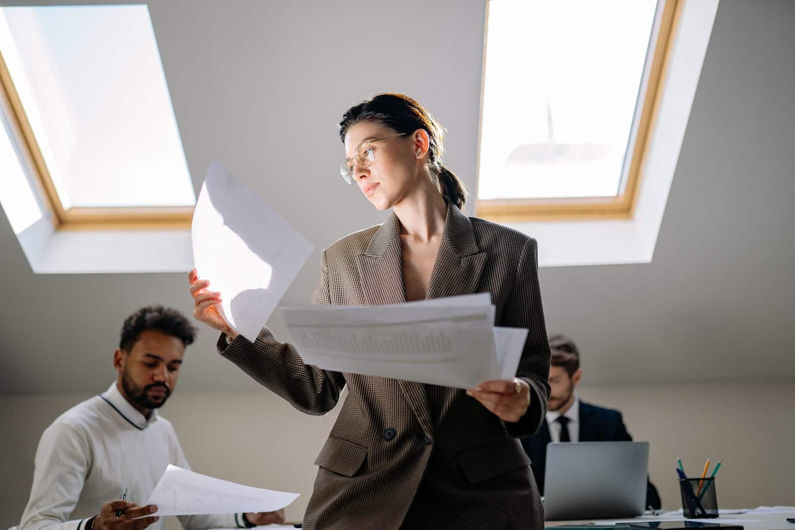 Team member reviewing paper documents with colleagues during an office discussion